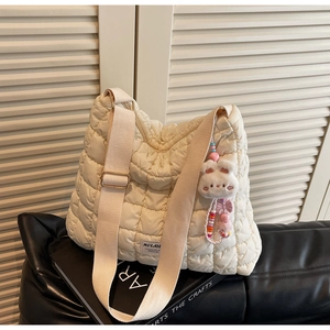 Detail of cream quilted puffer tote bag with wide strap and cute rabbit charm