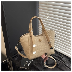 Detail of beige woven bucket bag featuring brown leather handles and adjustable metal buckle