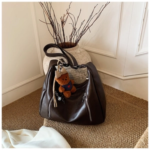 Detail of vintage brown shoulder bag with silver zippers and a cute plush bear charm