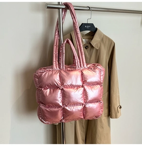 Detail of pink metallic quilted tote bag with padded texture hanging on metal rack