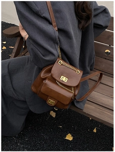 Detail eines braunen Ketten-Rucksacks mit goldenen Drehverschlüssen und Doppelklappe