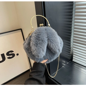 Gros plan d'un sac en peluche gris avec poignée dorée et fermoir vintage en métal
