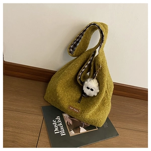 Detail of avocado green wool tote bag with soft texture and white plush charm