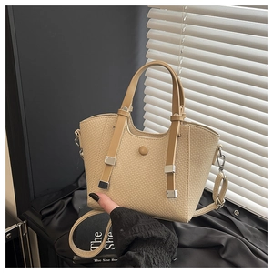 Detail of beige woven basket bag with brown leather handles and silver metal accents