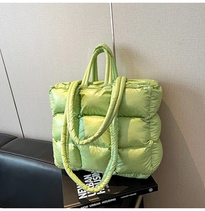 Detail of light green quilted puffer tote bag with dual straps and glossy nylon texture