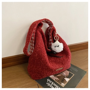 Macro shot of large red fuzzy hobo bag with red plaid lining and cute monster charm