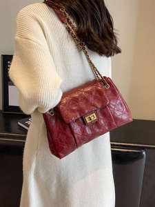 Retro deep red quilted crossbody bag with gold chain strap worn by a model in a knit dress
