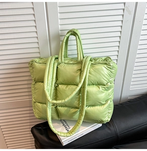 Macro shot of lime green quilted down tote bag with high-gloss nylon texture and square pattern