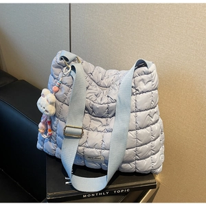 Detail of light blue quilted tote bag featuring a cute plush bunny charm and beaded decor