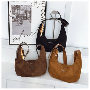 Detail of suede crescent bags featuring wooden bead charms and vintage leather straps