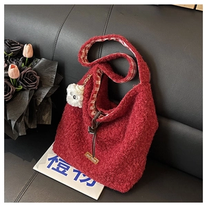 Close-up of red wool tote bag featuring plush texture and cute monster charm detail