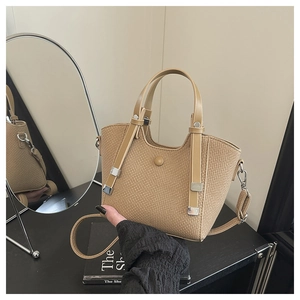 Detail view of woven leather basket bag with metallic clasp and adjustable crossbody strap