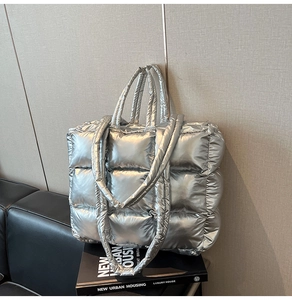 Detailed macro view of silver quilted down tote bag with metallic glossy fabric