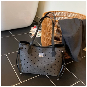 Detailed view of gray canvas tote bag with black polka dots and leather handles