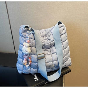 Detail of light blue quilted nylon tote with adjustable strap and plush rabbit charm