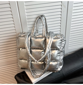 Close-up of silver quilted puffer tote bag with metallic finish on white shutter background
