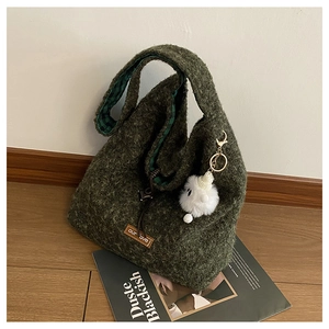 Detail of dark green knit tote bag with plush lamb charm and vintage plaid lining