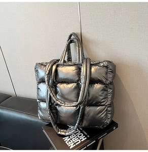 Close-up of metallic silver quilted tote bag with dual straps and glossy finish