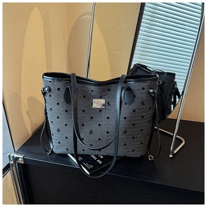 Detail of grey polka dot tote bag with leather trim and metallic brand plaque on front