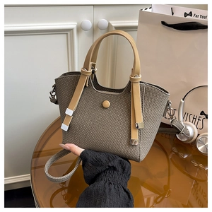 Detail of woven tote bag showing brown texture and khaki leather handle and round buckle