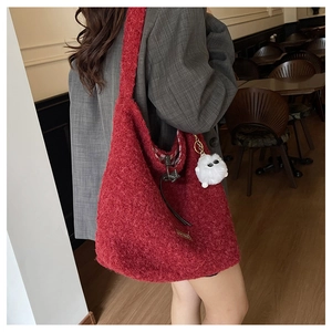 Detail view of red sherpa tote bag with soft texture and white pom-pom charm on model