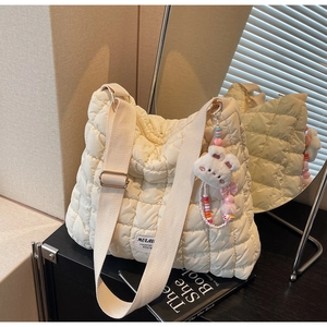 Detail of quilted puffer tote bag in cream color with cute white plush rabbit charm