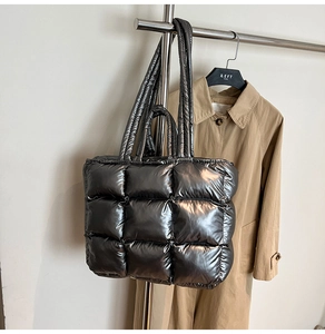 Detail of metallic grey quilted down tote bag showing puffy grid texture and thick straps