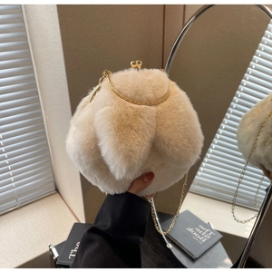 Détail du sac boule en peluche beige avec poignée dorée et texture en fausse fourrure