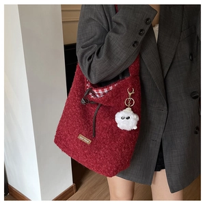 Detail of red fleece tote bag featuring brown leather tag and cute white plush charm