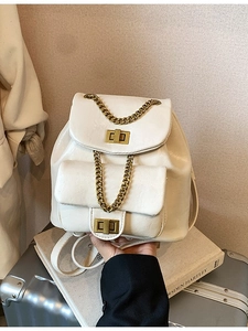 Rucksack aus weißem PU-Leder mit goldenen Ketten und Metallschnallen auf silbernem Koffer