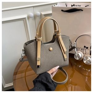 Detail of woven texture tote bag with leather straps and decorative round button closure