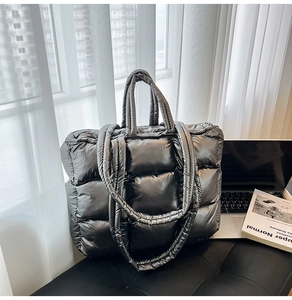 Quilted silver down tote bag showing large capacity and puffy metallic texture on a desk