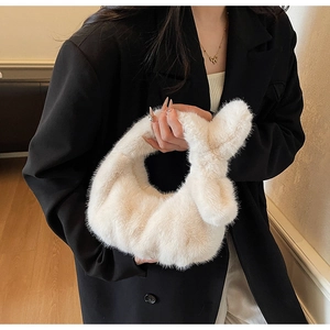 Dettaglio di una morbida borsa di peluche color crema abbinata a un elegante blazer nero