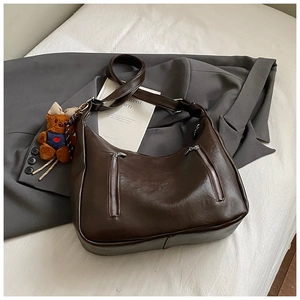 Detail of dark brown matte PU leather hobo bag featuring dual zippers and a cute bear charm