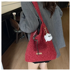 Detail of red fuzzy wool tote bag with soft texture and white monster plush keychain