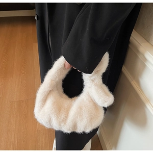 Détail de la texture d'un sac à main en fausse fourrure blanche sur un manteau