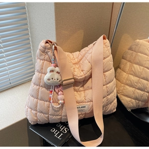Detailed view of pink quilted puffer bag with plush bunny charm and adjustable strap