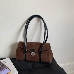 Close-up of deep brown suede shoulder bag with black leather straps and silver twist lock