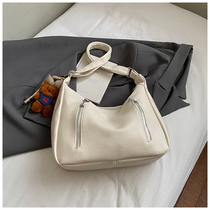 Detail of cream white leather hobo bag with silver zippers and a cute brown teddy charm