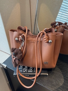 Borsa a secchiello in pelle marrone con finiture metalliche e ciondolo a forma di orso