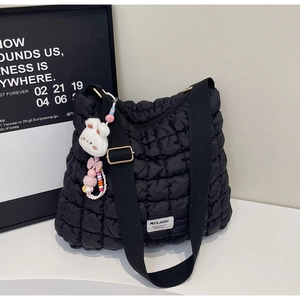 Detail of black quilted tote bag with golden hardware and cute rabbit plush charm