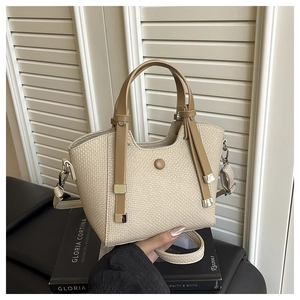 Close-up of beige woven texture bag with brown leather handles and silver hardware