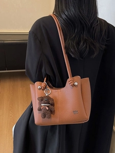 Borsa a secchiello in pelle marrone con spalline annodate e ciondolo a forma di orsetto