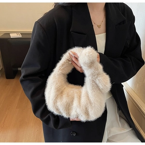 Dettaglio di una borsa a mano in peluche bianco panna con manico annodato e consistenza morbida