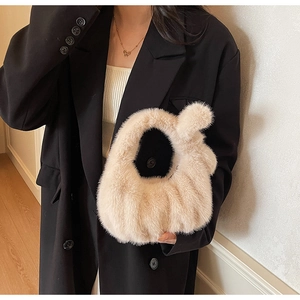 Dettaglio di una borsa in finta pelliccia beige abbinata a un blazer nero elegante