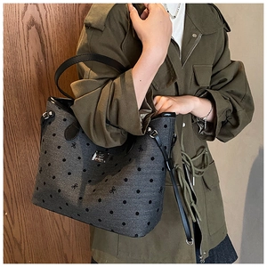 Polka dot tote bag with leather handles shown on shoulder with casual outfit