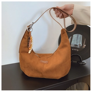 Detail of dark brown suede hobo bag with vintage wooden beads and logo plate on side