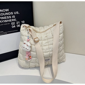 Detail view of quilted tote bag featuring adjustable strap and plush rabbit charm