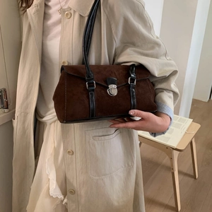 Close-up of brown suede hobo bag with sleek black strap and vintage silver metal buckle