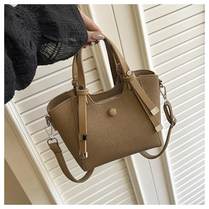 Detailed view of woven texture and adjustable shoulder strap on camel bucket bag